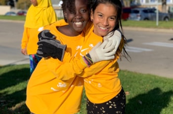 Two girls in yellow shirts hugging